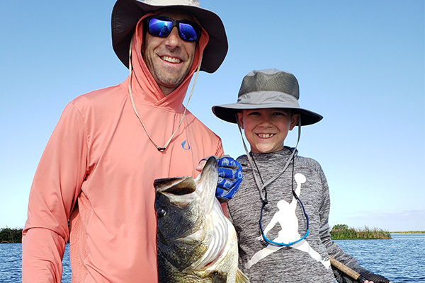 Man and boy holding a largemouth bass on Headwaters Lake and Stick Marsh in Vero Beach, FL